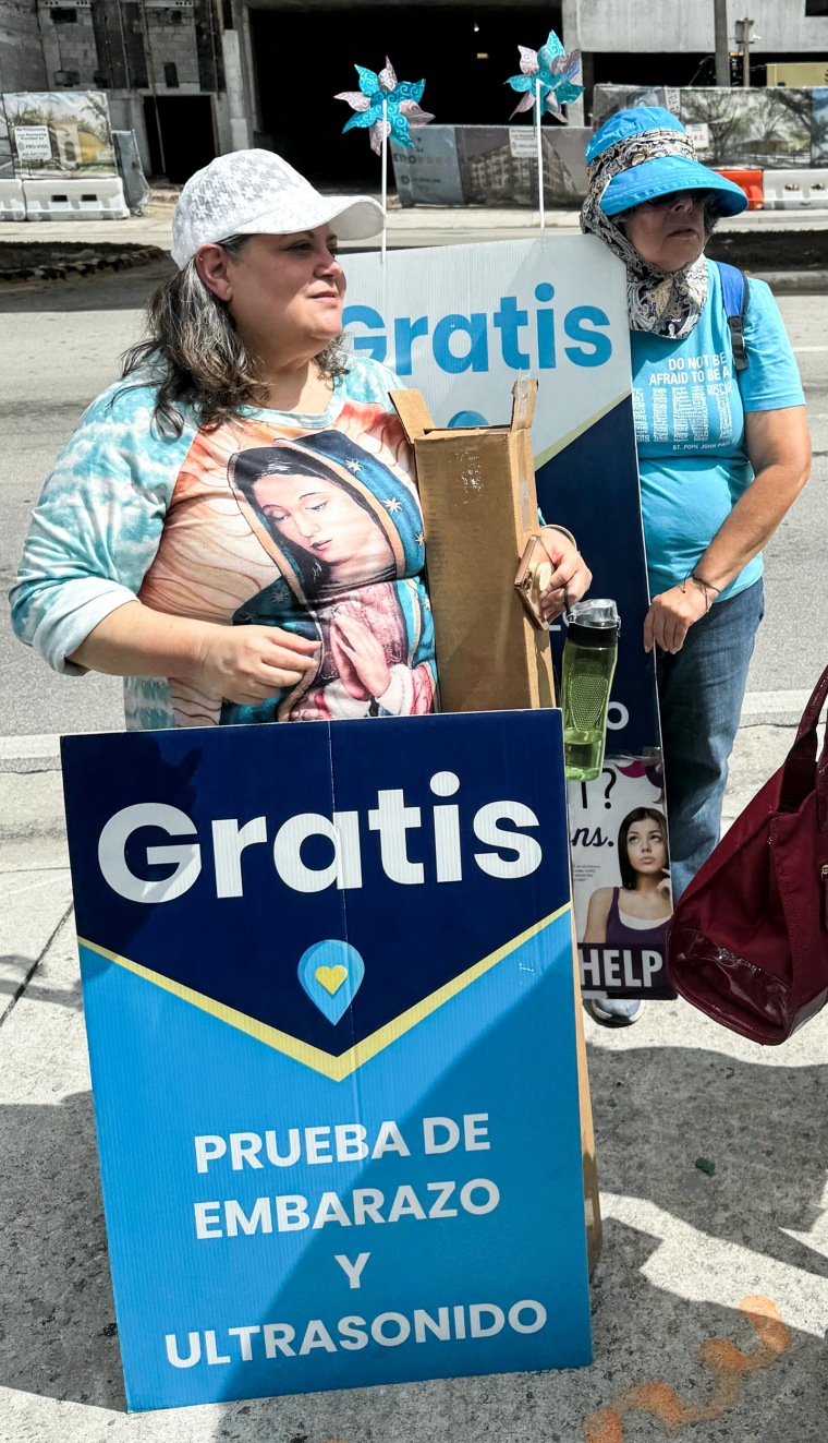 Pro-life demonstrators stand outside a clinic with signs in Spanish