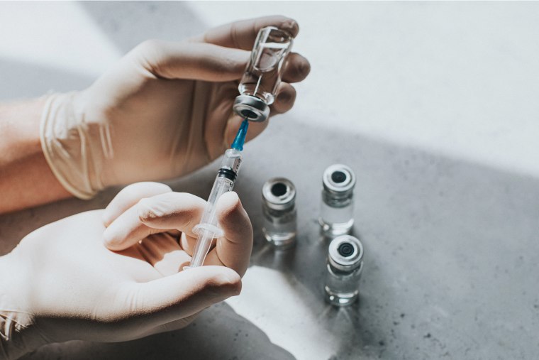 A person holding the vial of a vaccine