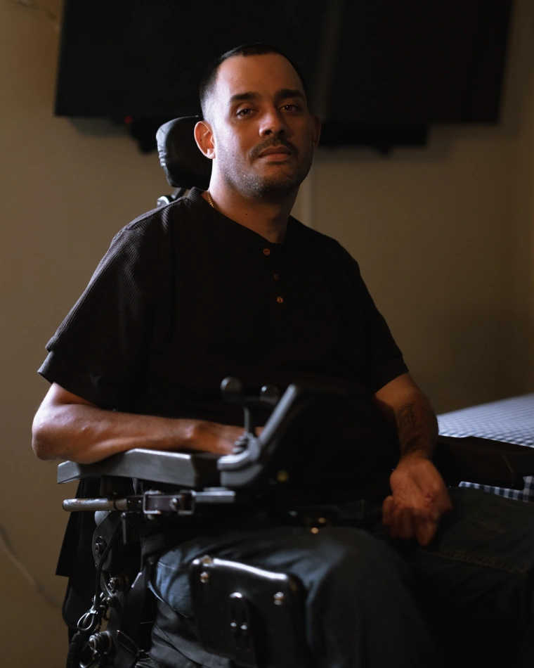 A Hispanic man in a black shirt in an electric wheelchair.